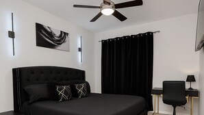 A modern bedroom with a large bed, a ceiling fan, a desk, and a chair. - Modern Executive Suite- NRG, Medical Center, Downtown Houston (Houston)