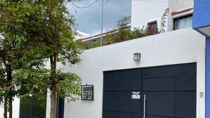 Un edificio moderno con una puerta de garaje negra, un ventanal pequeño y un letrero que indica que no se permite estacionar.