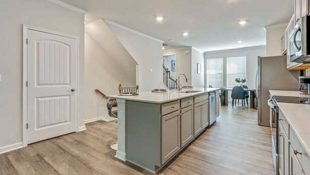 A modern kitchen with a central island, built-in appliances, and a dining area with a chair and table.