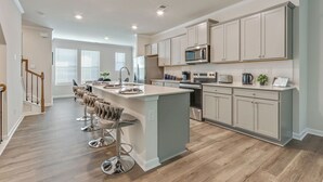 A modern kitchen with a central island, bar stools, and built-in appliances.