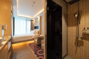 Una habitación de hotel moderna con cama, zona de estar, ducha y baño.