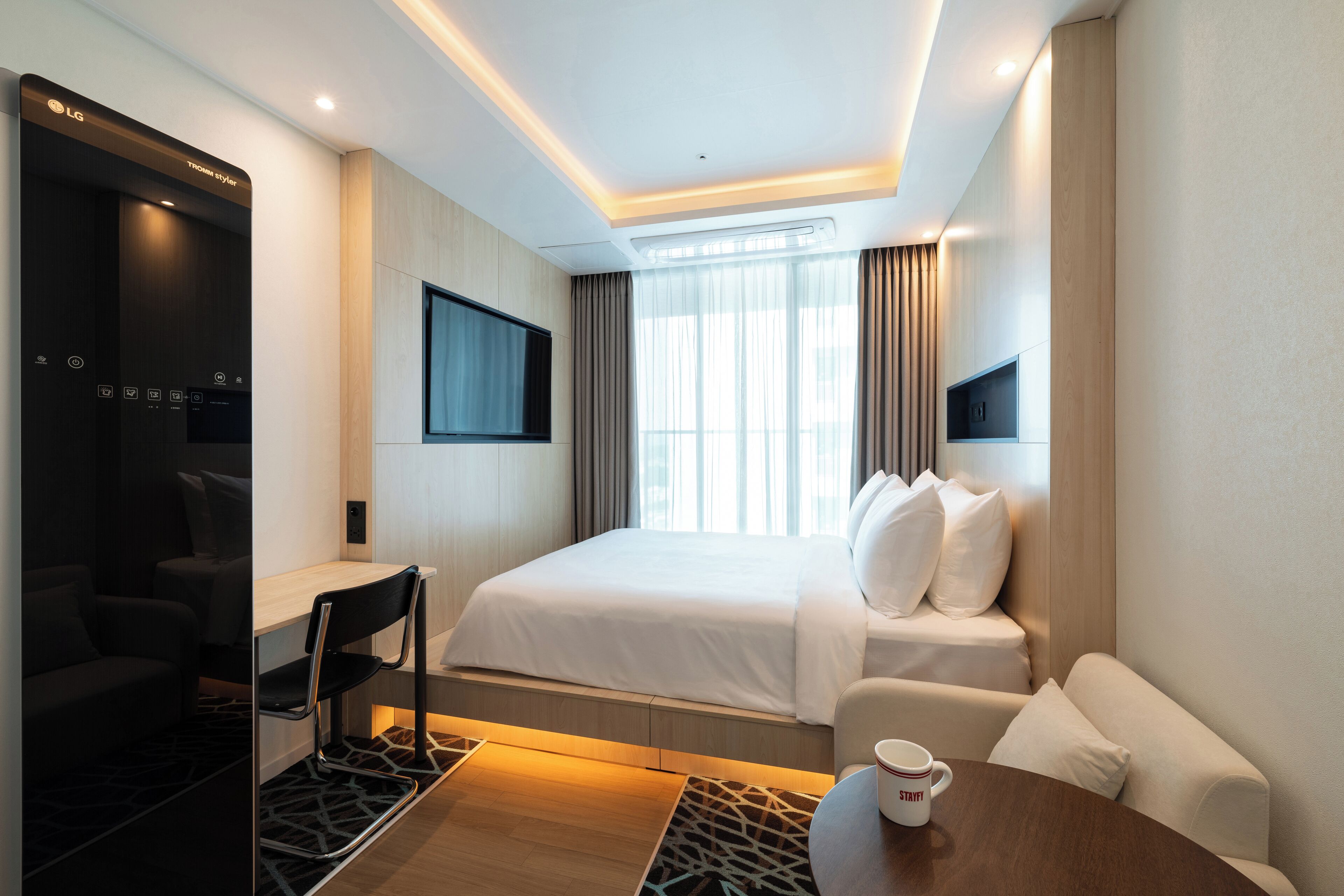 Ein Hotelzimmer mit Bett, Schreibtisch, Stuhl, Fernseher und Couchtisch.