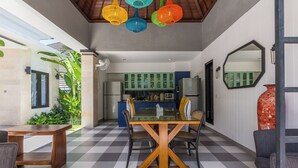 Una cucina moderna con mobili verdi, un'isola centrale e un'area pranzo con pavimento a scacchi.