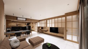 Un salon moderne avec un canapé, un pouf et une table basse. On y trouve également un coin repas avec des chaises et une table, ainsi qu'une cuisine équipée d'un téléviseur.
