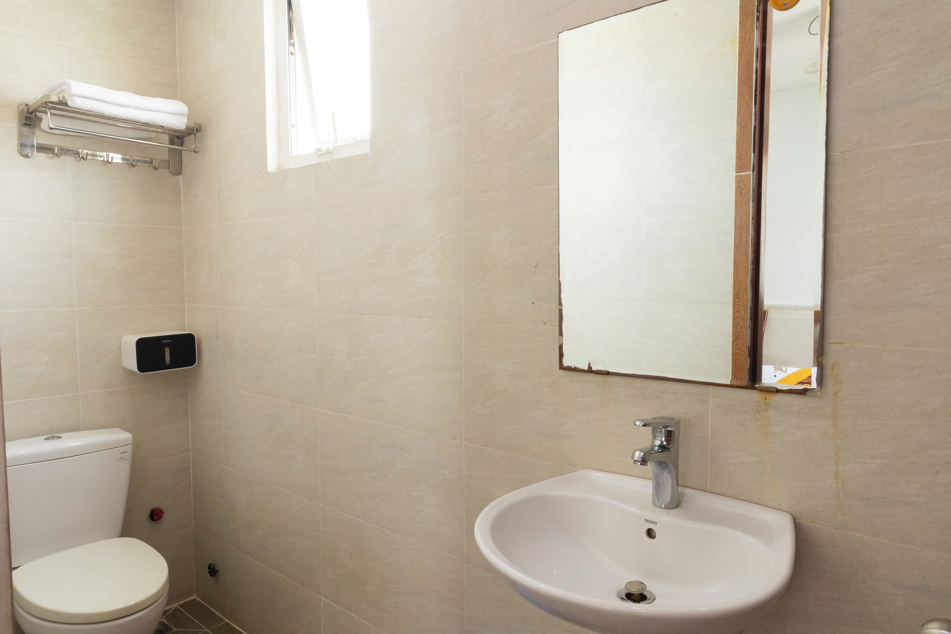 Casa de banho com sanita, lavatório e porta-toalhas.