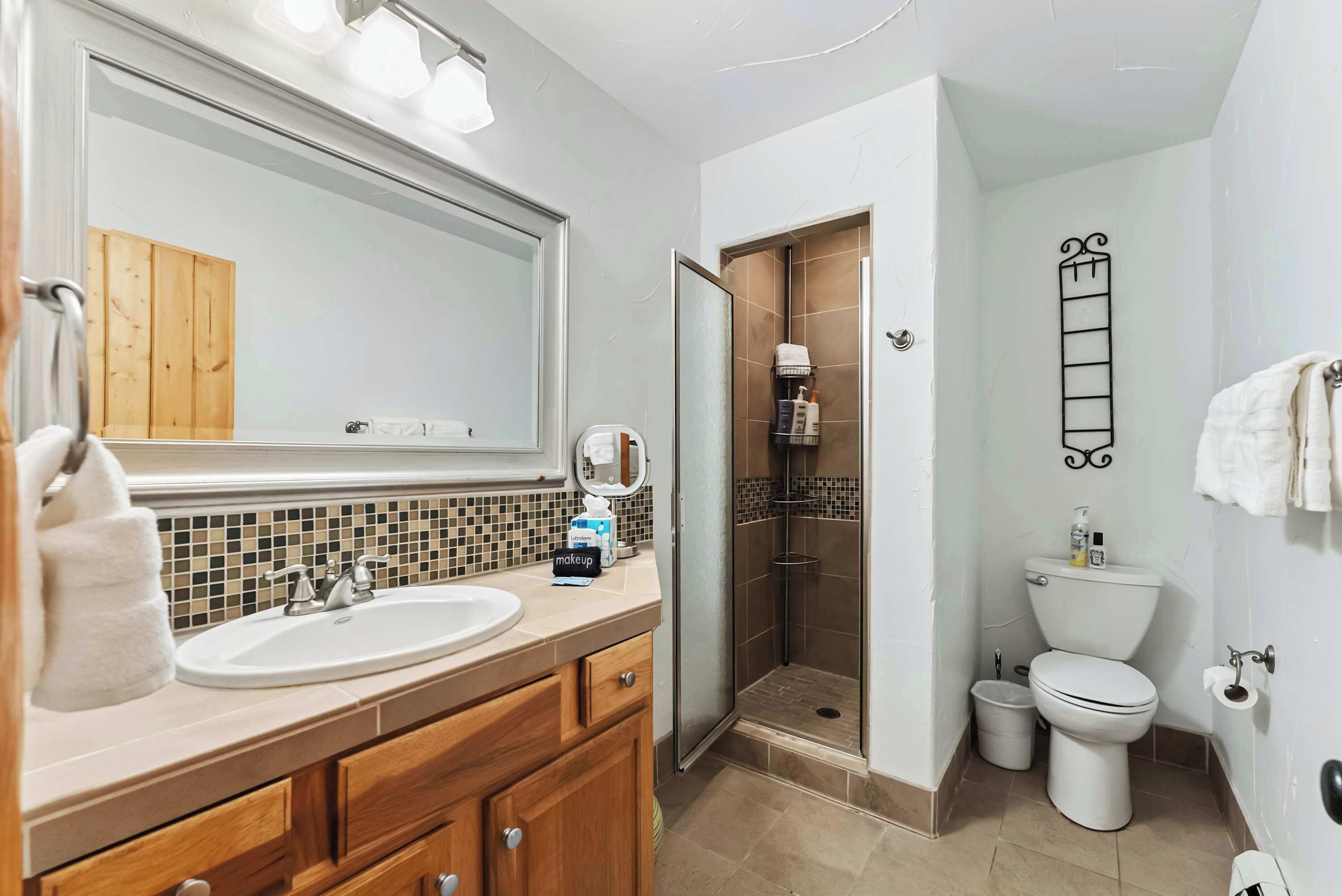 A bathroom with a sink, mirror, and a shower enclosure.