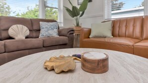 Un salon avec une table ronde, un canapé en cuir marron, un objet décoratif en forme de feuille et une tasse en bois.