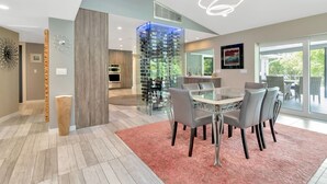 A modern dining area with a glass table, grey chairs, and a pink rug. - Papys Preserve | Luxury Waterfront Estate w/ Pool (St Petersburg)