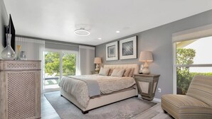 A bedroom with a bed, two bedside lamps, a dresser, and a chair. - Papys Preserve | Luxury Waterfront Estate w/ Pool (St Petersburg)