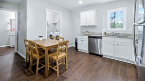 A modern kitchen with white cabinets, stainless steel appliances, and a wooden dining table. - Clemson Weekend Rental- very close to campus, 4 Bedroom 3 Bathroom (Clemson)