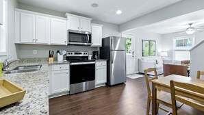 A modern kitchen with white cabinets, stainless steel appliances, and a wooden dining table. - Clemson Weekend Rental- very close to campus, 4 Bedroom 3 Bathroom (Clemson)