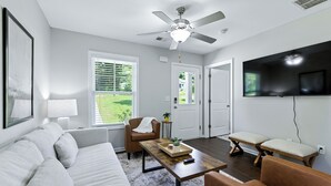 A living room with a sofa, armchair, coffee table, and a television mounted on the wall. - Clemson Weekend Rental- very close to campus, 4 Bedroom 3 Bathroom (Clemson)