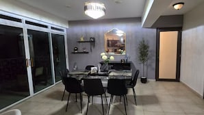Comedor con separador de vidrio, una araña y un espejo en la pared.