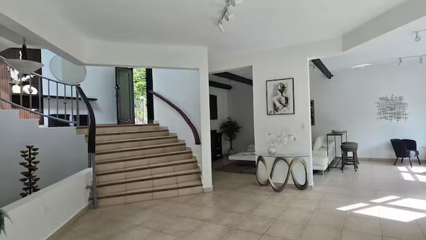 Amplia sala de estar con escalera, una mesa de comedor y sillas.