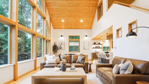 A spacious living area with large windows, a wooden ceiling, and a cozy seating arrangement.