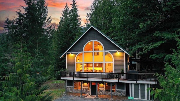 A two-story house with a balcony, surrounded by trees.