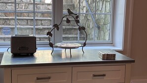 A desk with a radio, a decorative metal piece, and a bowl of fruit.