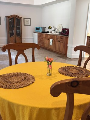Ein Essbereich mit einem gelben Tisch, zwei Holzstühlen und einer Blumenvase.