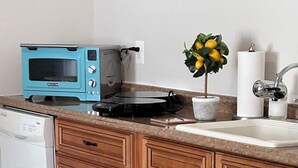 A kitchen with wooden cabinets, a blue toaster, a sink, and a potted plant.