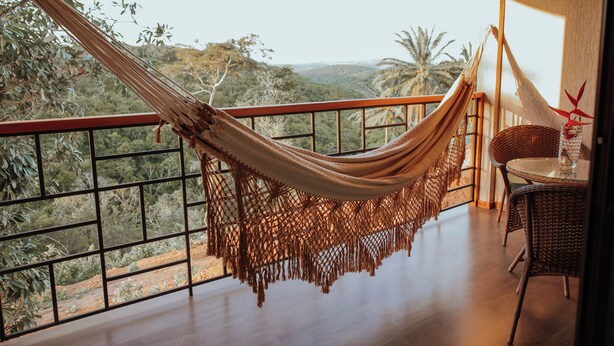 Een hangmat op een balkon met uitzicht op een bergachtig landschap.