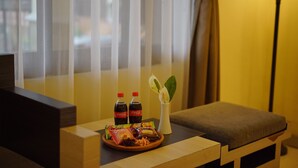 A room with a wooden bench, a tray with snacks and drinks, and a vase with a plant. - Tripletree Ken Hotel (Cisarua)