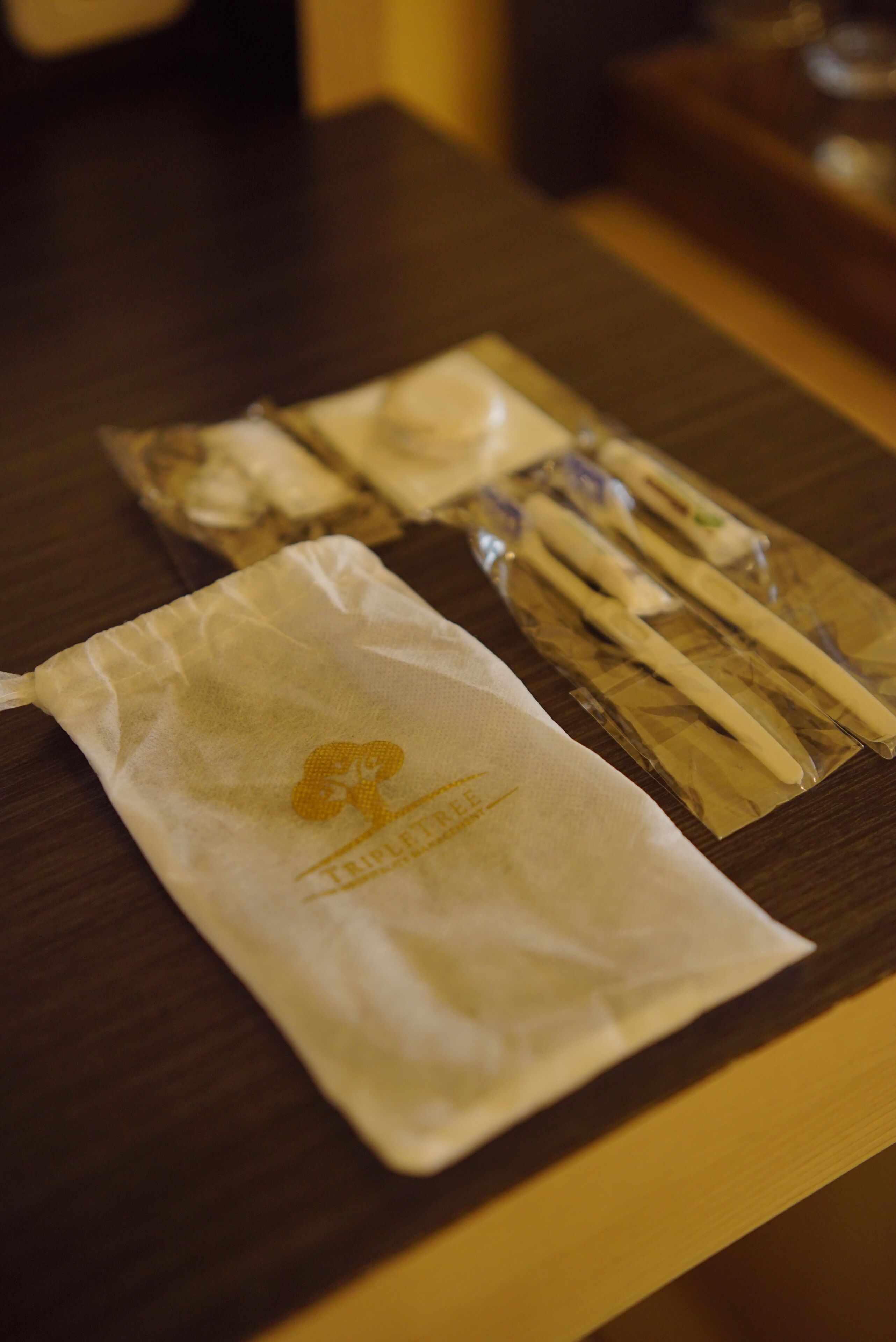 A table with a white cloth bag and a plastic bag containing chopsticks and a small item.