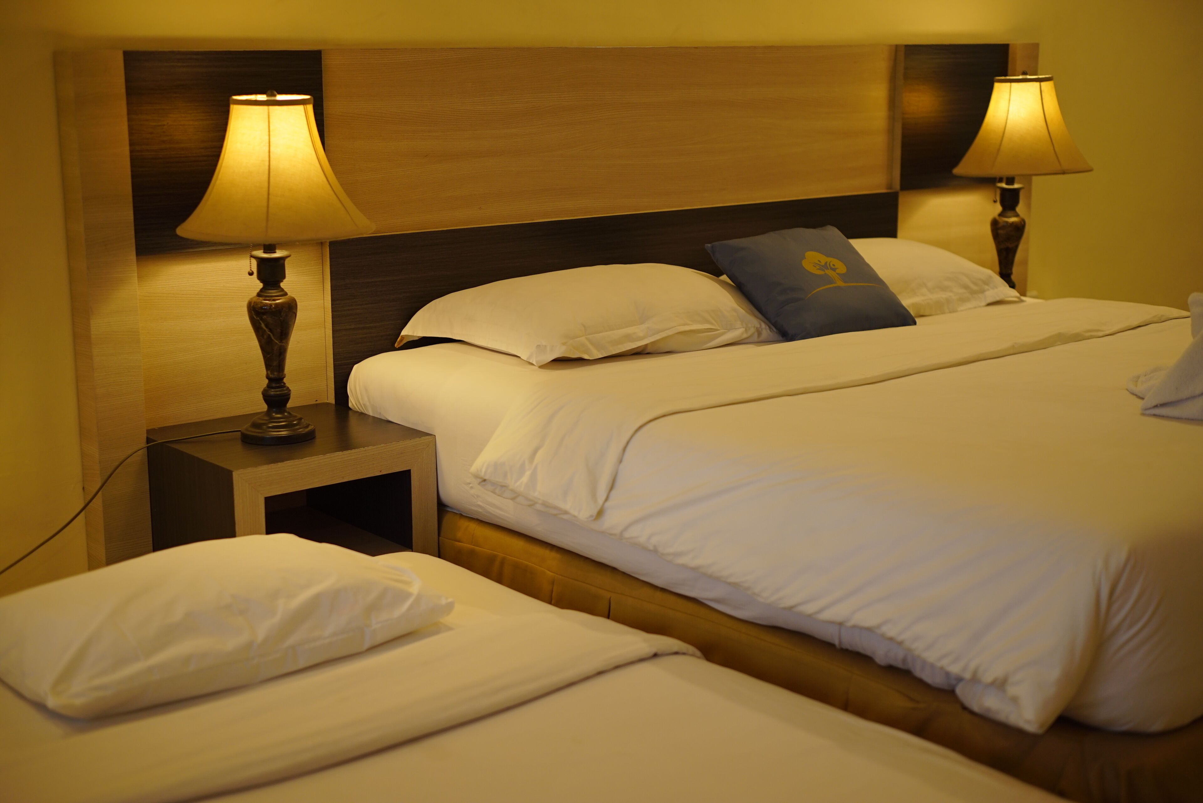 A hotel room with a double bed, two bedside tables with lamps, and a headboard.