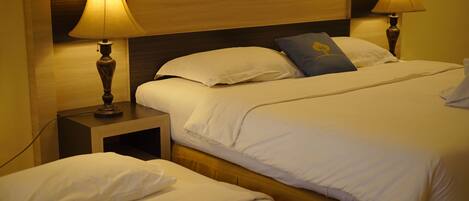 A hotel room with a double bed, two bedside tables with lamps, and a headboard.