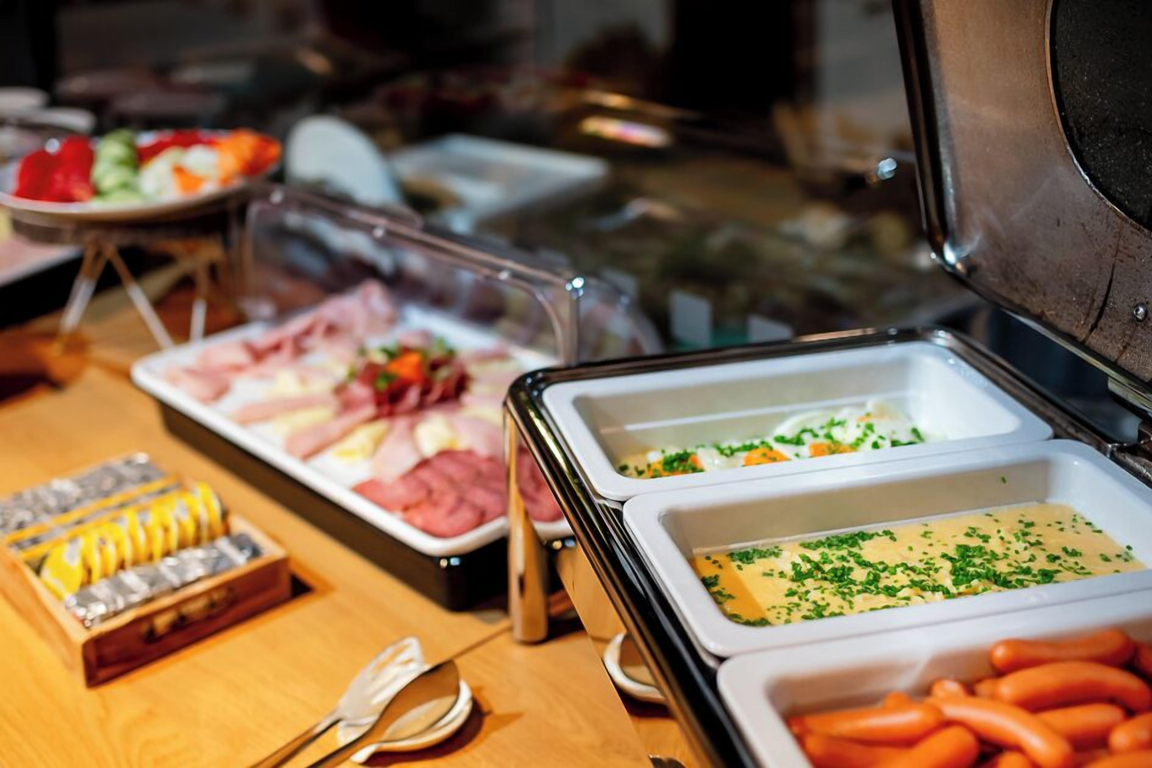 A buffet with various food items including meats, cheeses, and vegetables.