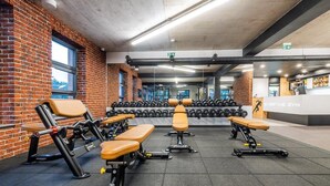A gym with weightlifting equipment, benches, and dumbbells.