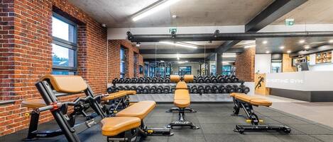 A gym with weightlifting equipment, benches, and dumbbells.
