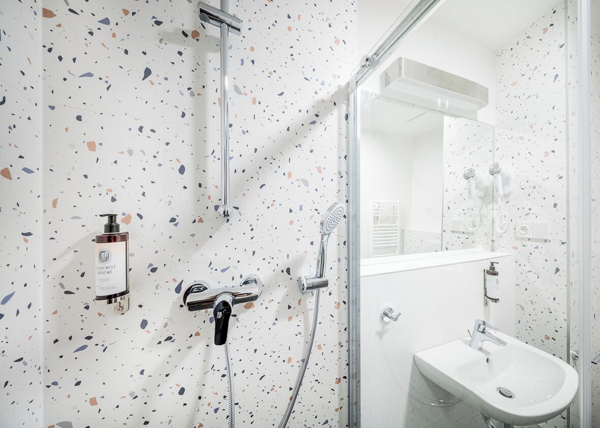 Un baño moderno con ducha, lavamanos y espejo.