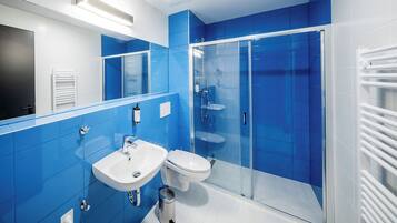A modern bathroom with blue tiles, a glass-enclosed shower, and a white sink.