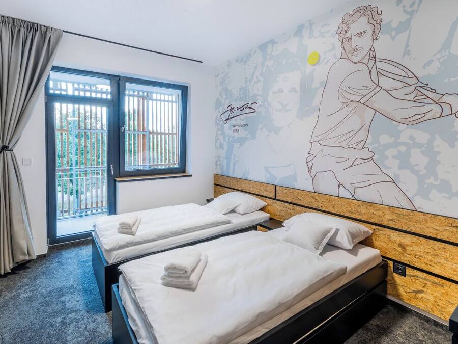A hotel room with two beds, a large window with a view, and a mural on the wall.