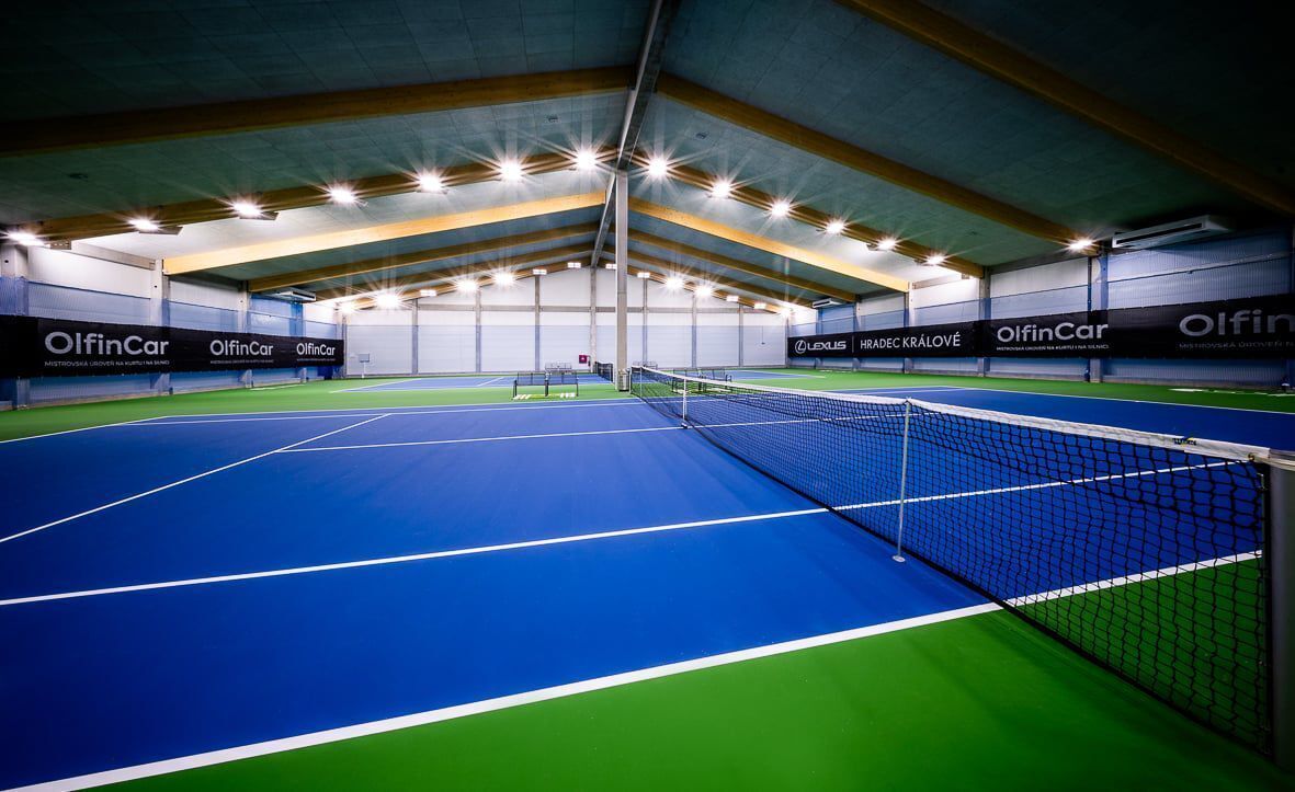 Un court de tennis intérieur, doté d’un filet et entouré de murs sur lesquels sont affichées des publicités.