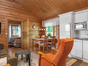 A cozy cabin interior with a dining area, kitchen, and a living space with a sofa and a small table.