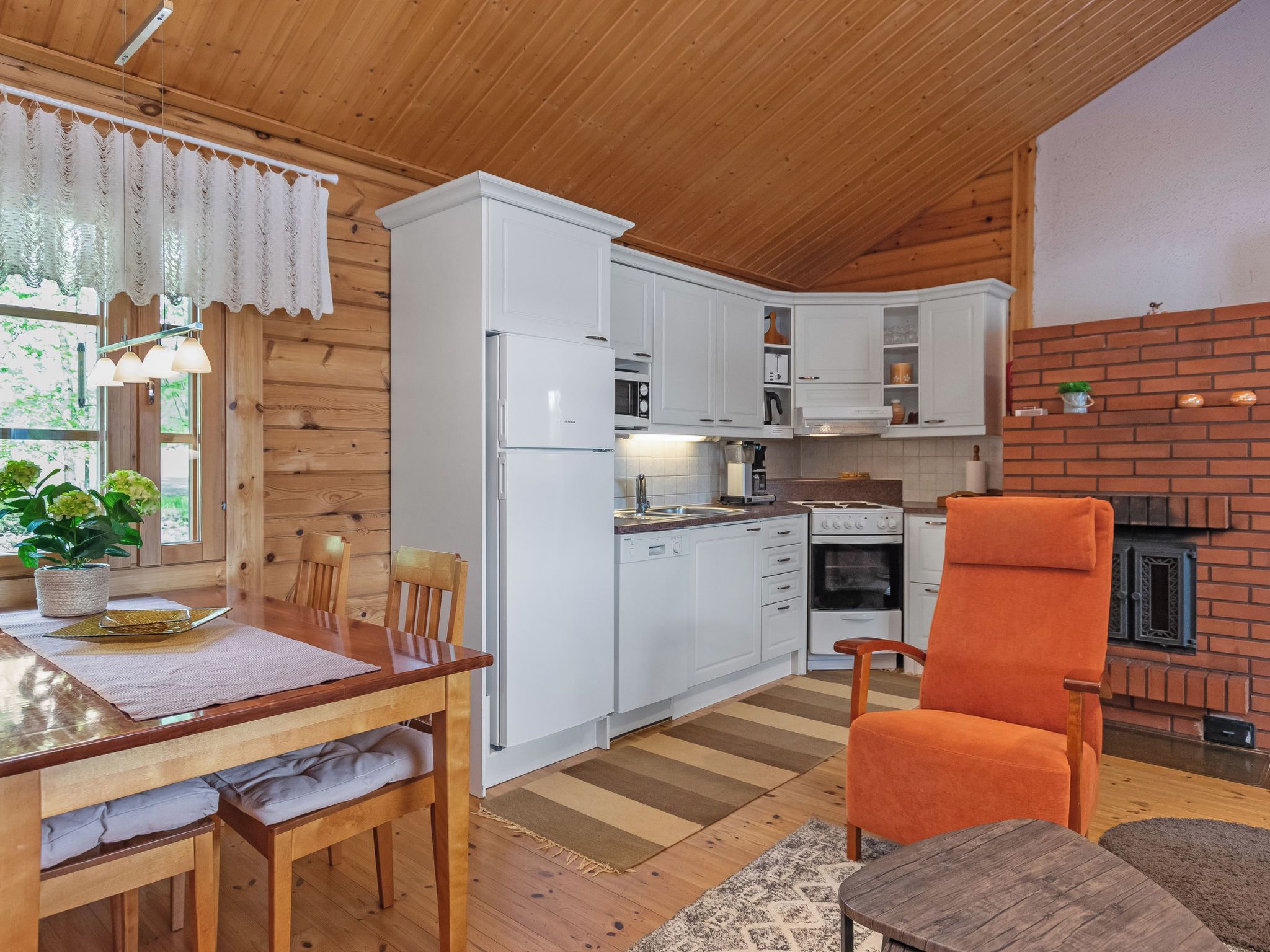 A compact kitchen with white cabinetry, a built-in oven, and a brick fireplace.