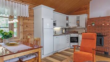 A compact kitchen with white cabinetry, a built-in oven, and a brick fireplace.