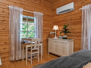 A wooden cabin room with a desk, chair, and a bed.