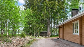 A cabin with a gravel driveway, surrounded by trees and a stone wall. - Hiekkaranta by Interhome (Pertunmaa)