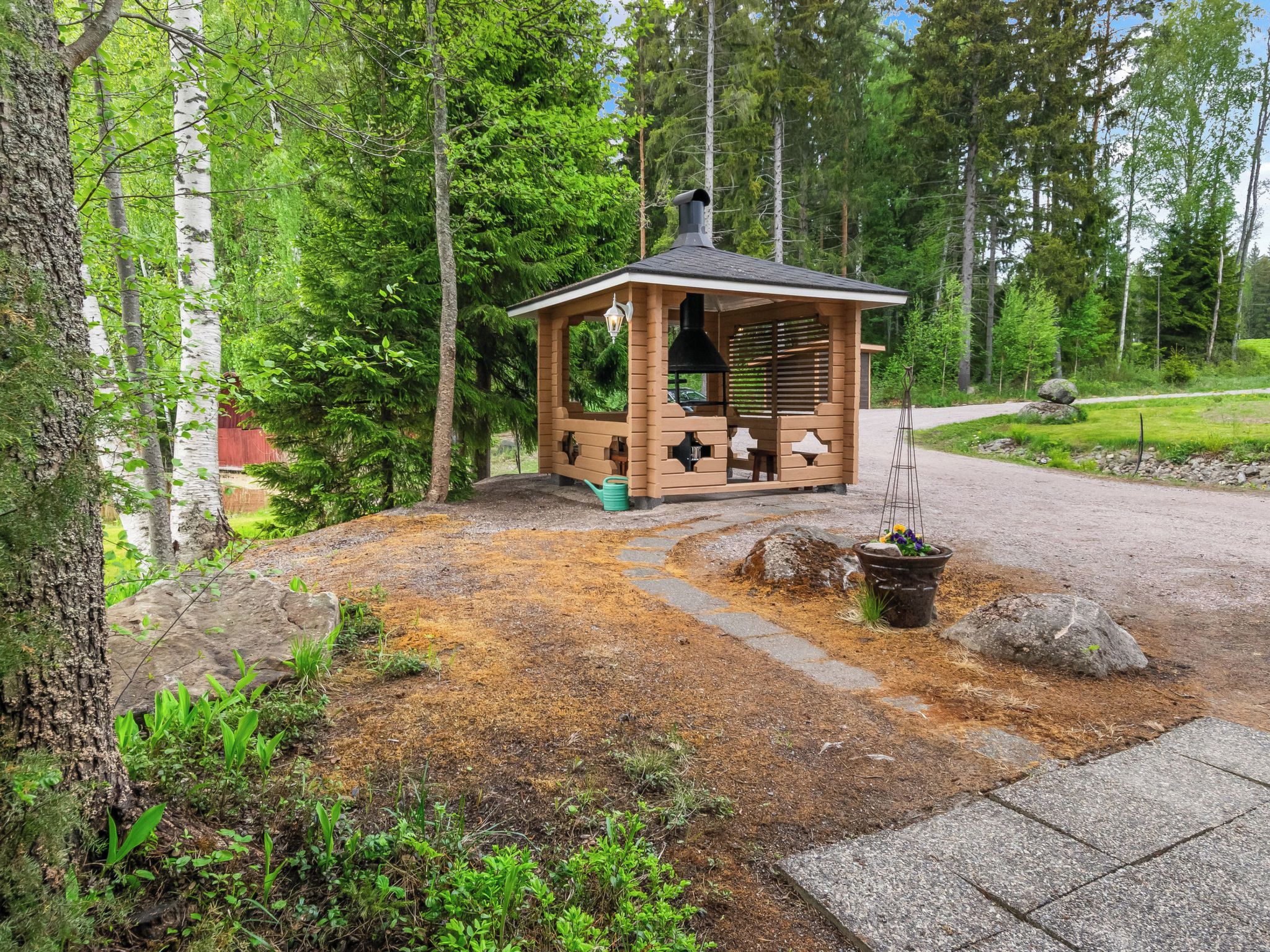 A wooden cabin with a chimney, surrounded by a forest.