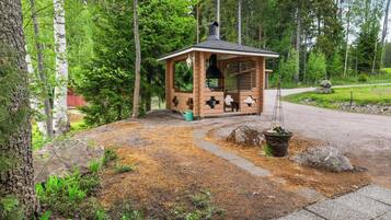 A wooden cabin with a chimney, surrounded by a forest.