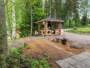 Una cabaña de madera con chimenea, rodeada de un bosque.