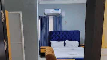 Une chambre d’hôtel avec un lit, une chaise et un appareil de climatisation.