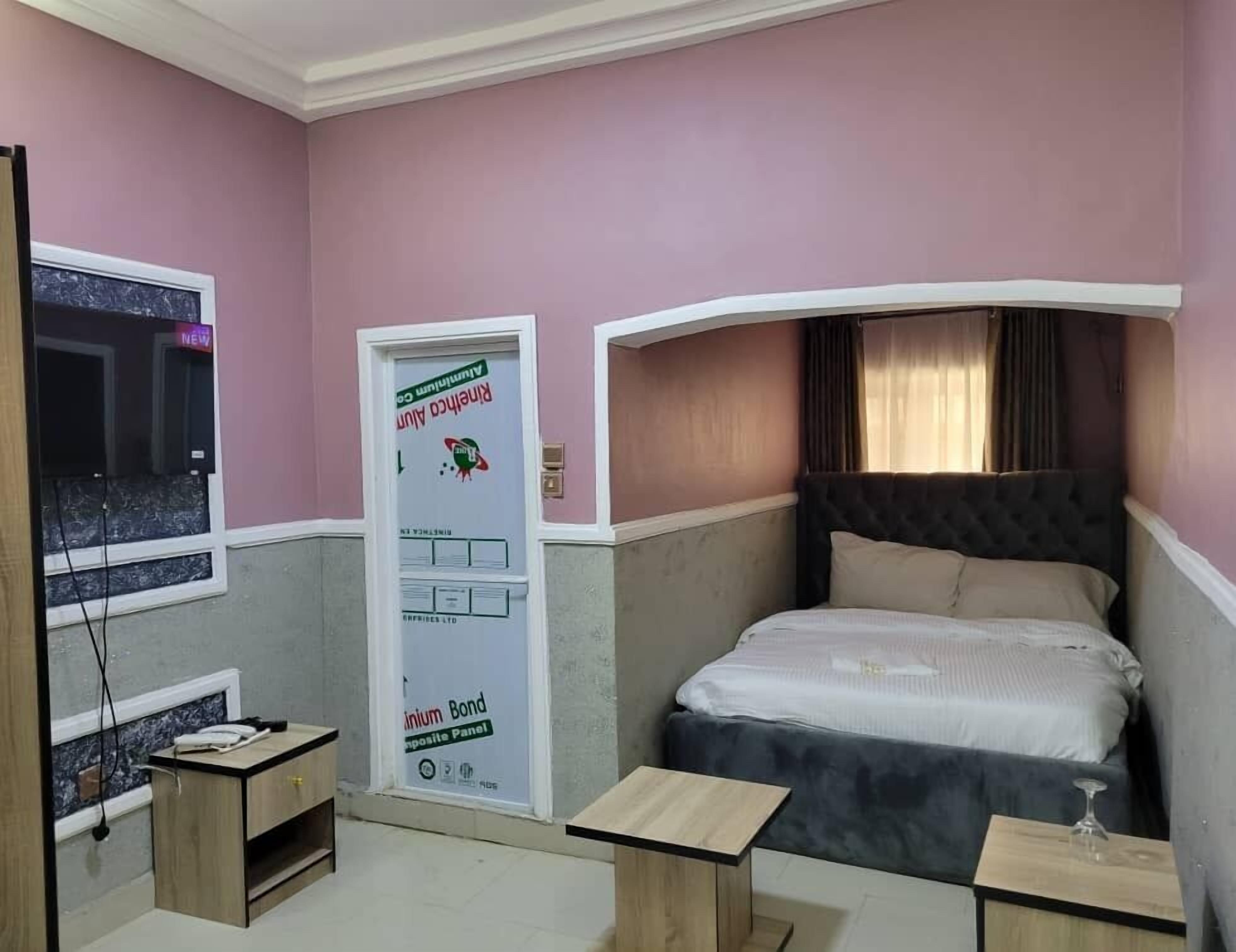 A bedroom with a bed, a desk, and a window.