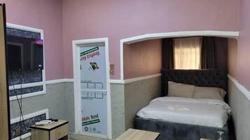 A bedroom with a bed, a desk, and a window.