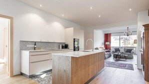 Eine moderne Küche mit Kochinsel, Holzschränken und einer Essecke mit Sofa und Tisch.