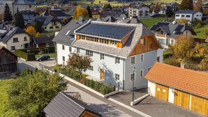 A residential area with a prominent white building featuring a sloped roof and solar panels.