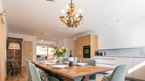 A modern kitchen with wooden cabinets, a dining table set for four, and a chandelier.