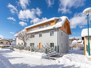 A two-story house with a snow-covered roof and a wooden balcony.